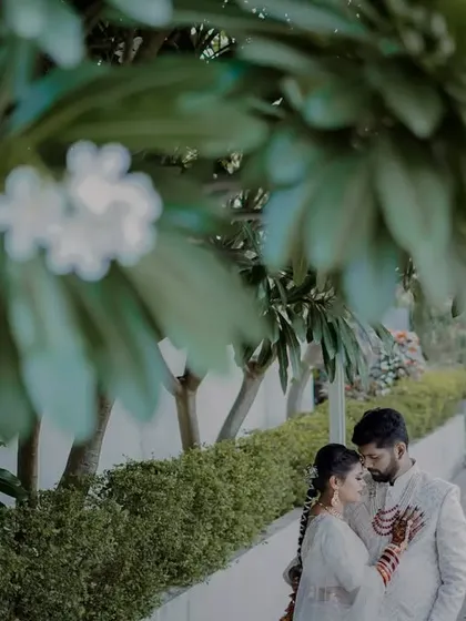 A creative shot using foreground blur from the trees to frame the couple, adding depth and an artistic touch to the portrait.