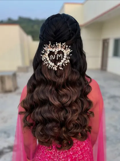 The beauty of a hairstyle lies in the details. This personalized initial accessory adds a unique and meaningful touch to the classic wavy half-updo.