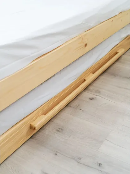 A close-up of the trundle bed's handle, seamlessly carved into the wooden frame for a clean and minimalist look.