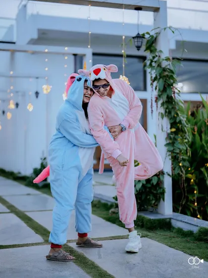 A fun and quirky shot of a couple in animal onesies, hugging and laughing in a garden setting.