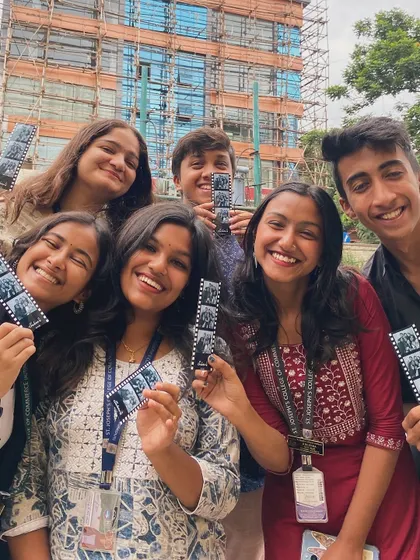 All smiles from this group, showing off their collection of photo strips against the backdrop of their college campus.