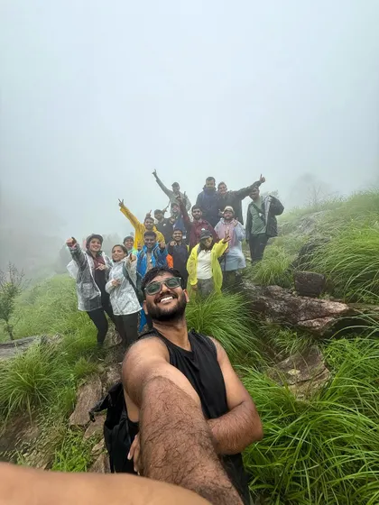 A trek lead takes a selfie with the entire group on the grassy, misty slopes of the Bandaje trek. The fun and energy are contagious.