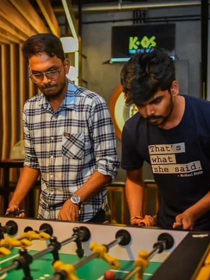 That "what she said" t-shirt perfectly captures the vibe of a foosball game here. It's all laughs and intense focus as two friends battle it out on the table.