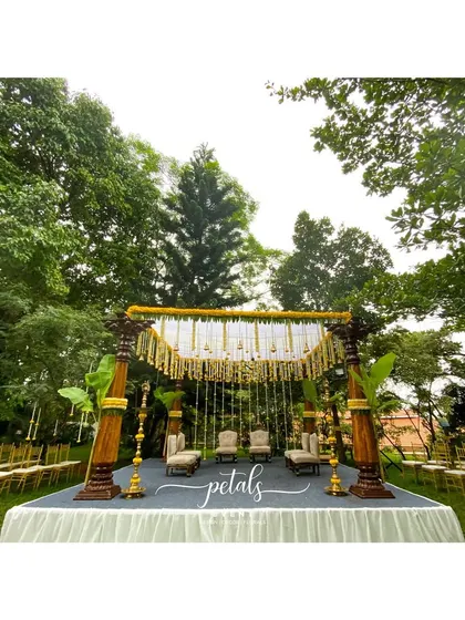 An elevated view of the mandap, showing the full scope of the decor. The combination of wooden pillars, marigolds, and traditional bells creates a sacred space that is both elegant and deeply rooted in heritage.