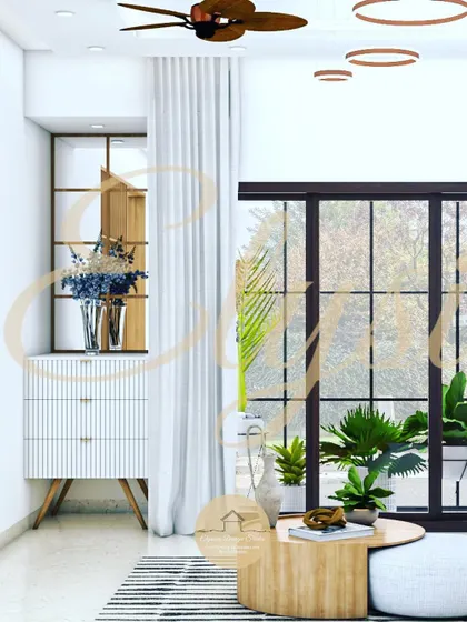 A living area design for a project at Adarsh Serenity, Bangalore. This render showcases a bright, airy space with large windows, a comfortable tan leather sofa, and natural wood elements for a modern and inviting feel.
