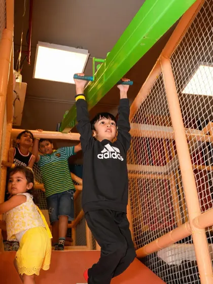 Another view of a young guest enjoying the monkey bars, a fun and challenging part of our play zone.