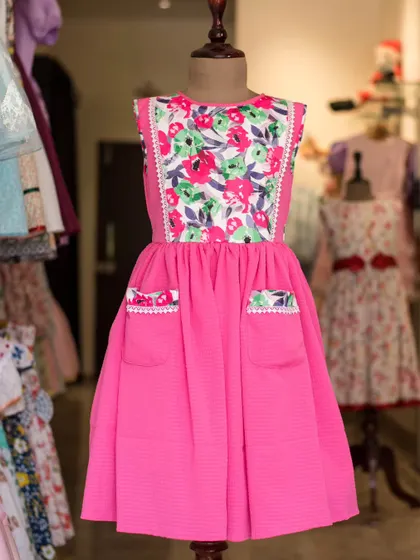 A full view of the bright pink dress with the floral bodice, showcasing its fun and functional design.