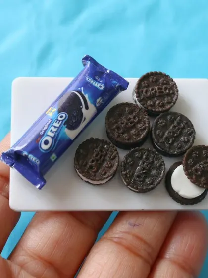 A close-up of a miniature Oreo biscuit packet and the tiny, cream-filled cookies.