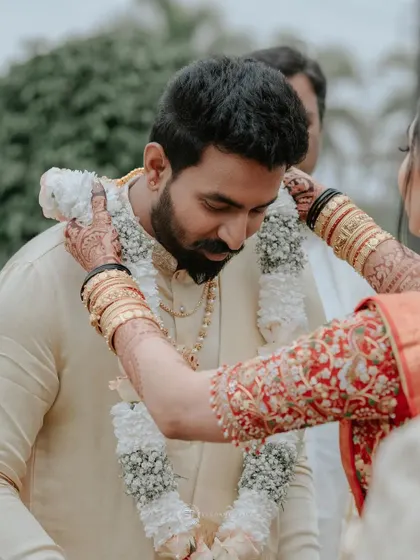A beautiful moment from Arpita's wedding, where the rich stain of her mehendi is visible as she places the garland on her groom.