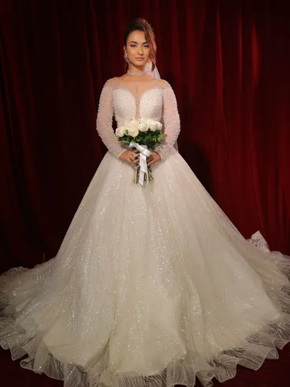Holding her bouquet, this bride is the picture of perfection. The entire look, from the gown to the makeup, is a seamless blend of grace and style.