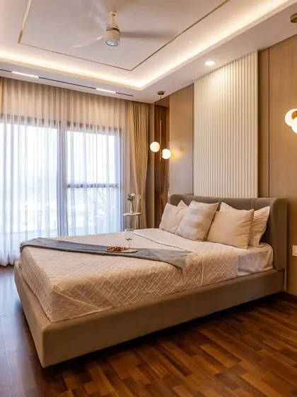 A full view of the bedroom layout, showing the placement of the bed, a small vanity table by the window, and the use of mirrors to enhance the room's dimensions.