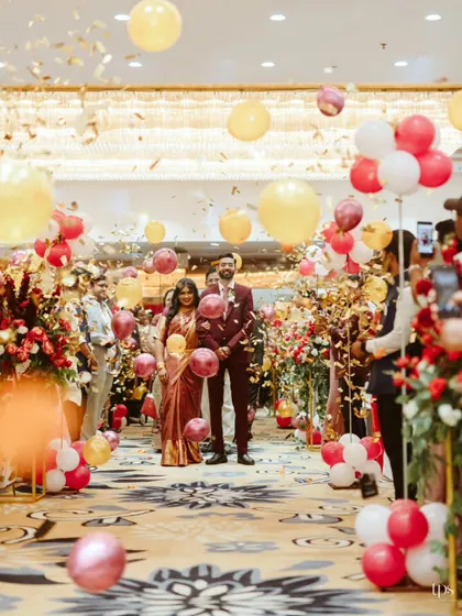 A grand welcome for the newlyweds. Jerin and Gladys made their entrance through a shower of confetti and balloons, walking down an aisle lined with lush floral arrangements, creating a festive and joyous atmosphere.