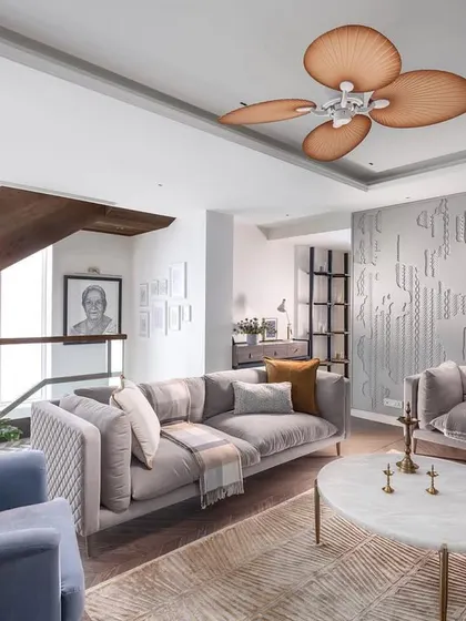 Another view of the Amara living room, showcasing the comfortable, minimalist furniture and a unique, petal-like ceiling fan. The space is designed to be open and airy, with fewer walls to promote a sense of harmony.
