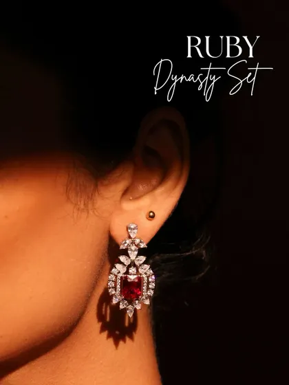 A close-up of the Ruby Dynasty earring, highlighting the regal brilliance of the central ruby framed by a halo of sparkling diamonds.