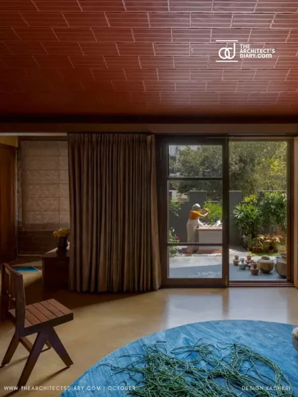 The living room seamlessly connects to the outdoors, with large glass doors opening onto the deck and garden, inviting nature inside.