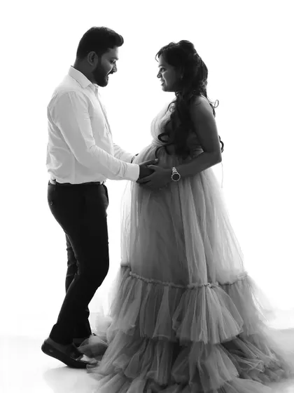 A classic black and white couple's portrait, showcasing the elegant silhouette of the mom-to-be in her gown.