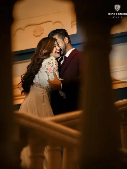 Laughter echoing through the halls of a Jaipur hotel. This candid shot, framed through a railing, feels like a stolen moment of pure happiness, showcasing the fun and joy behind the formal pre-wedding photos.