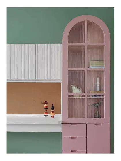 For a child's room, we designed this candy-floss pink cabinet with fluted glass. It provides ample storage for toys and books, while the arched top and sage green walls create a playful and imaginative atmosphere.