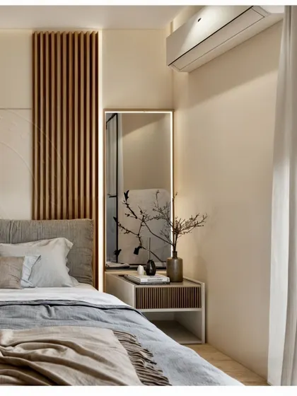 This bedroom corner shows how to create a cozy sanctuary using warm neutral colors and soft lighting. The vertical wood paneling behind the bed adds texture and visual interest, complemented by a simple, elegant bedside table and a backlit mirror. It's a perfect example of how to use layered textures to make a space feel inviting.