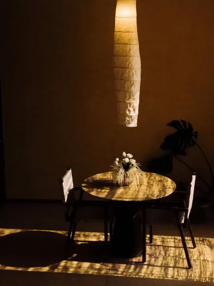 A small dining table catches the golden hour light, creating an intimate and warm spot for a private meal or a cup of tea.