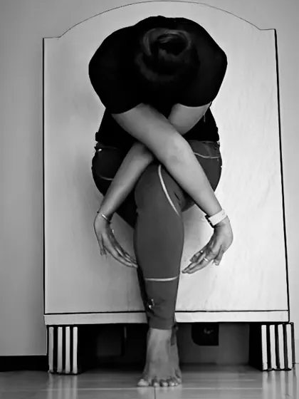 A black and white shot of 'Infinity Eagle Pose', highlighting the intricate bind of the arms and the strength required in the legs to hold the pose.