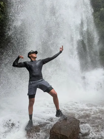 A trekker strikes a pose on a rock in the middle of a powerful stream at Kodachadri.