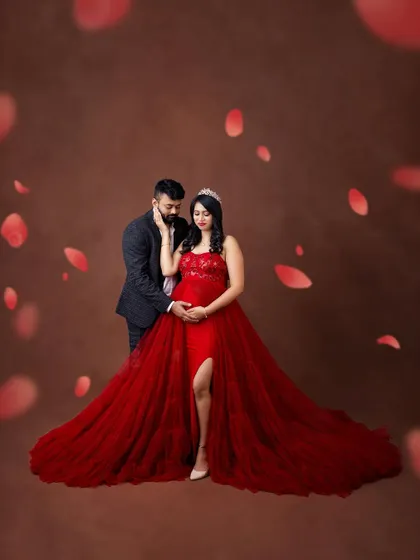 A royal moment for the expecting parents. The tiara, the flowing red gown, and the romantic pose create a fairytale-like portrait.