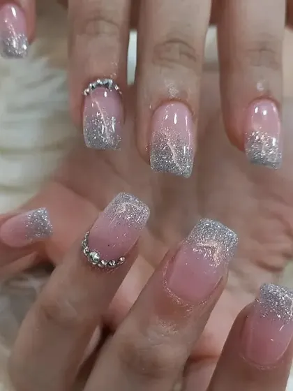 A soft and elegant design featuring a sheer pink base with a silver glitter gradient from the tips, accented with a line of rhinestones at the cuticle.