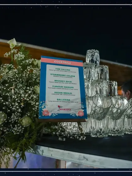 A close-up of our custom cocktail menu displayed on an easel, surrounded by fresh flowers and sparkling glassware. Every detail is thoughtfully arranged to enhance the guest experience.