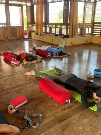 The studio is a sanctuary of calm during a Yin yoga session, with students resting deeply in supported postures.