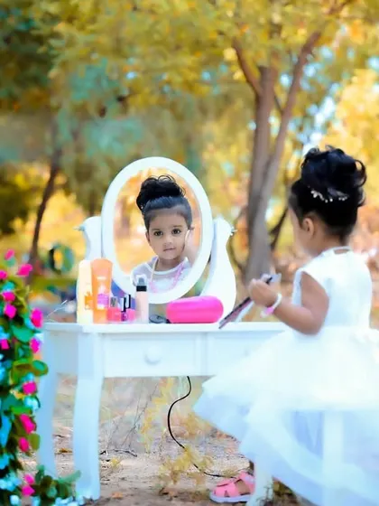 An outdoor makeup-themed shoot with a little girl at a vanity table in a park setting.