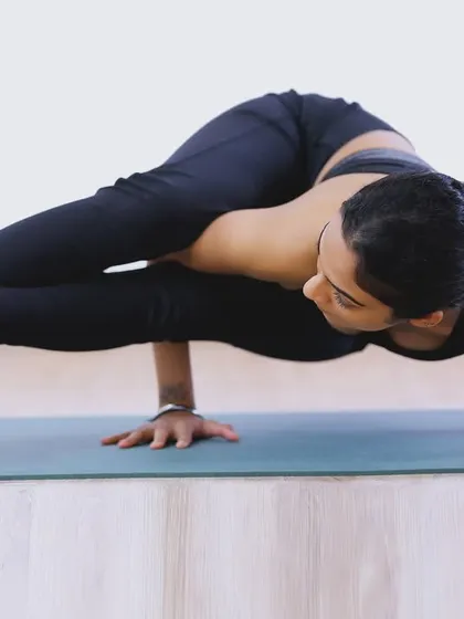 Holding Astavakrasana (Eight-Angle Pose), an arm balance that requires core strength, hip flexibility, and a strong connection between mind and body.