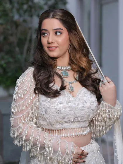 A beautiful portrait of our bride-to-be. The natural, soft glam makeup enhances her features, and the voluminous waves add a touch of glamour to her white ensemble.
