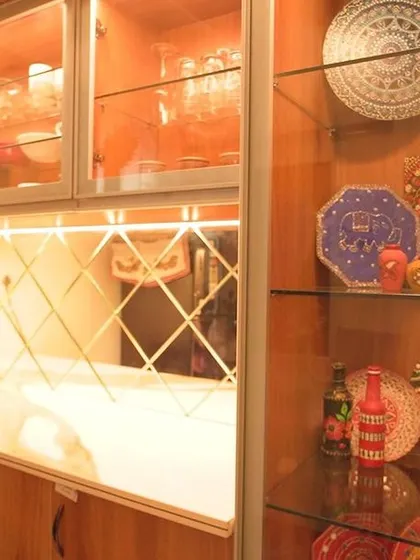 A close-up of a beautiful crockery unit with glass display shelves filled with colorful decorative plates. The internal lighting highlights the collection, turning it into a piece of art.