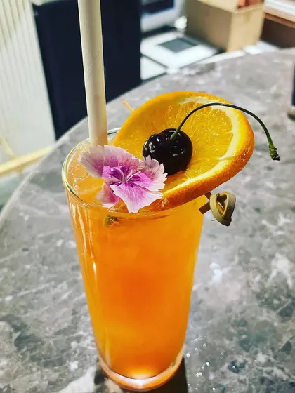 A classic and refreshing orange cocktail. Garnished simply with a slice of orange, a cherry, and an edible flower, this drink is perfect for a summer event.