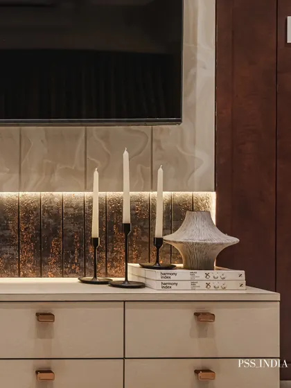 A perfectly styled console. Slender candle holders, a textured ceramic vase, and a stack of art books create a balanced and sophisticated vignette, enhanced by the warm glow of backlighting.