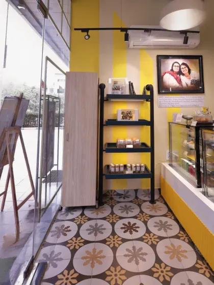 The entrance of Ditya Bakehouse offers a welcoming glimpse into the cheerful interior. The patterned tiles draw the eye inward, and the open shelving provides a space for displaying retail products.