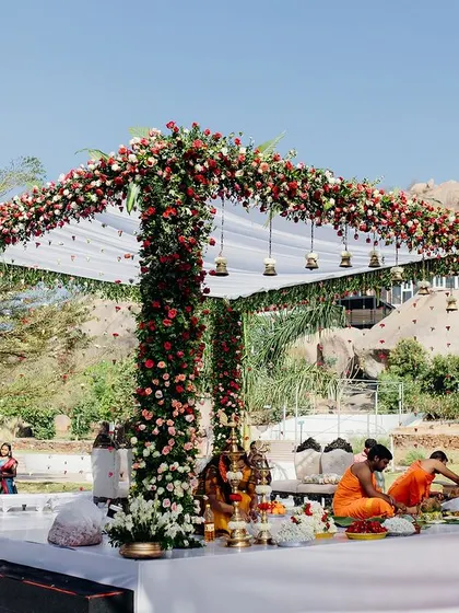 A closer look at the wedding ceremony in progress within the floral mandap. The design provides a beautiful frame for the couple and the rituals, enhancing the sanctity and beauty of the moment.