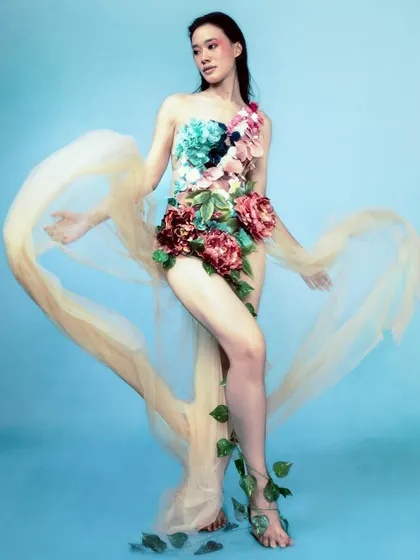 A graceful, full-length pose against a blue background, with sheer fabric creating a heart shape around the model. This shot adds a touch of romanticism to the tragic narrative.