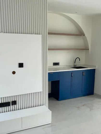 The nearly completed lounge, showing the fluted TV wall next to the newly installed blue pantry. This image captures the interplay of textures and colors that define the modern space.