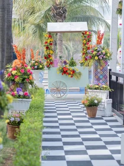 The entrance to the carnival-themed event, featuring a black and white checkered path lined with colorful floral arrangements.