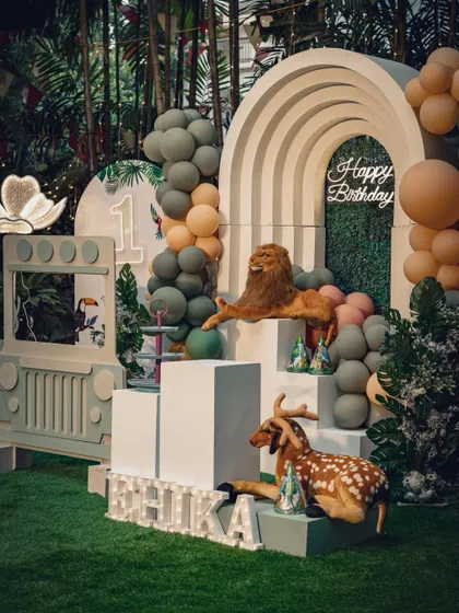 A beautiful safari-themed birthday setup for a little one. The design features a custom jeep photo booth, animal props, and a lush green backdrop, perfect for an outdoor or indoor jungle adventure.