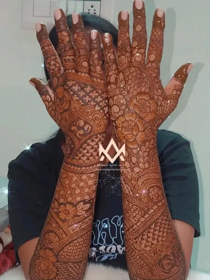 Showcasing a complete bridal mehendi look, with intricate details covering every part of the hands and forearms.