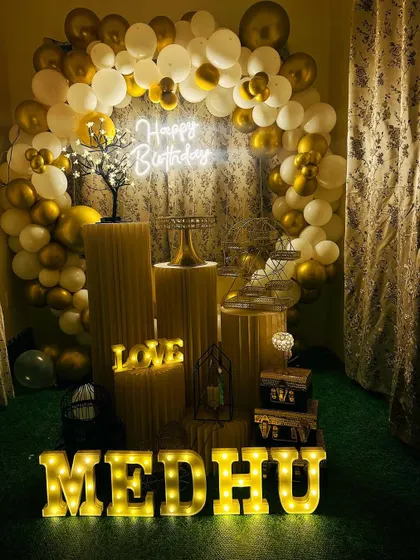 An elegant gold and white themed birthday setup on a green turf, showing the versatility of my decorations for different floorings.