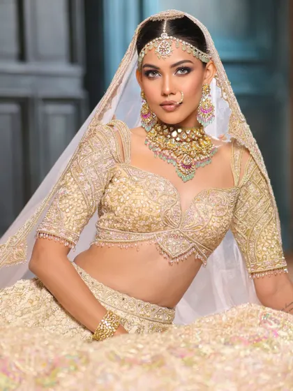 A full-length shot showcasing the stunning detail of the ivory lehenga. The makeup is designed to complement the outfit, creating a look of pure elegance.