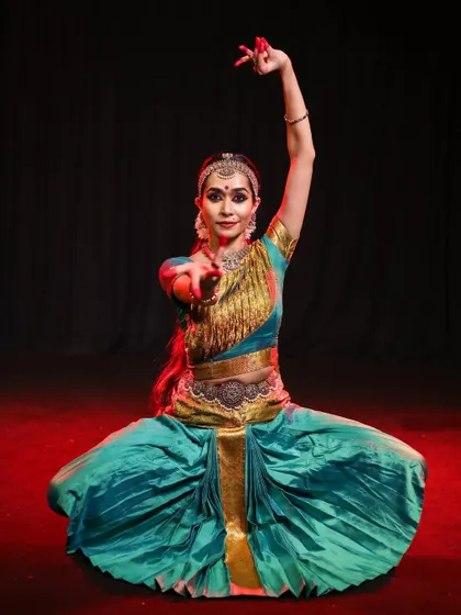 A full-body capture of a traditional Bharatanatyam stance, highlighting the vibrant costume and the dancer's grounded yet graceful posture on stage.