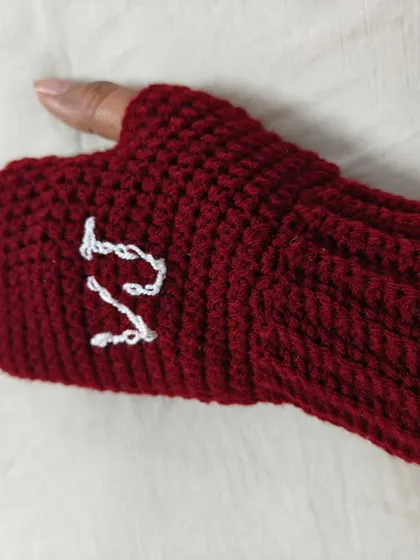 A close-up of the personalized maroon gloves, showing my initial 'V' for Vanya Yarn Designs. I can add any initials you want to make your pair truly special.