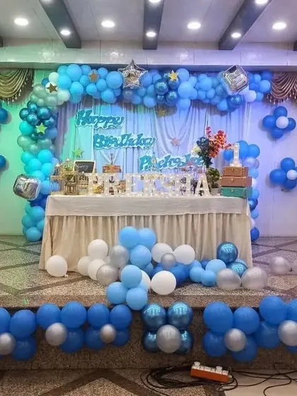 A simple yet grand stage decoration with blue and silver balloons, perfect for birthdays or other celebrations in a hall.