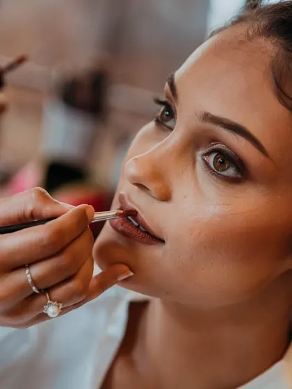 A close-up of the makeup artist applying lipstick, focusing on the precision and artistry of bridal makeup.