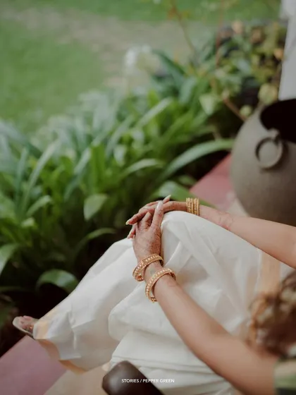 A detail shot of the bride's hands and her beautiful kasavu saree, a moment of quiet elegance.